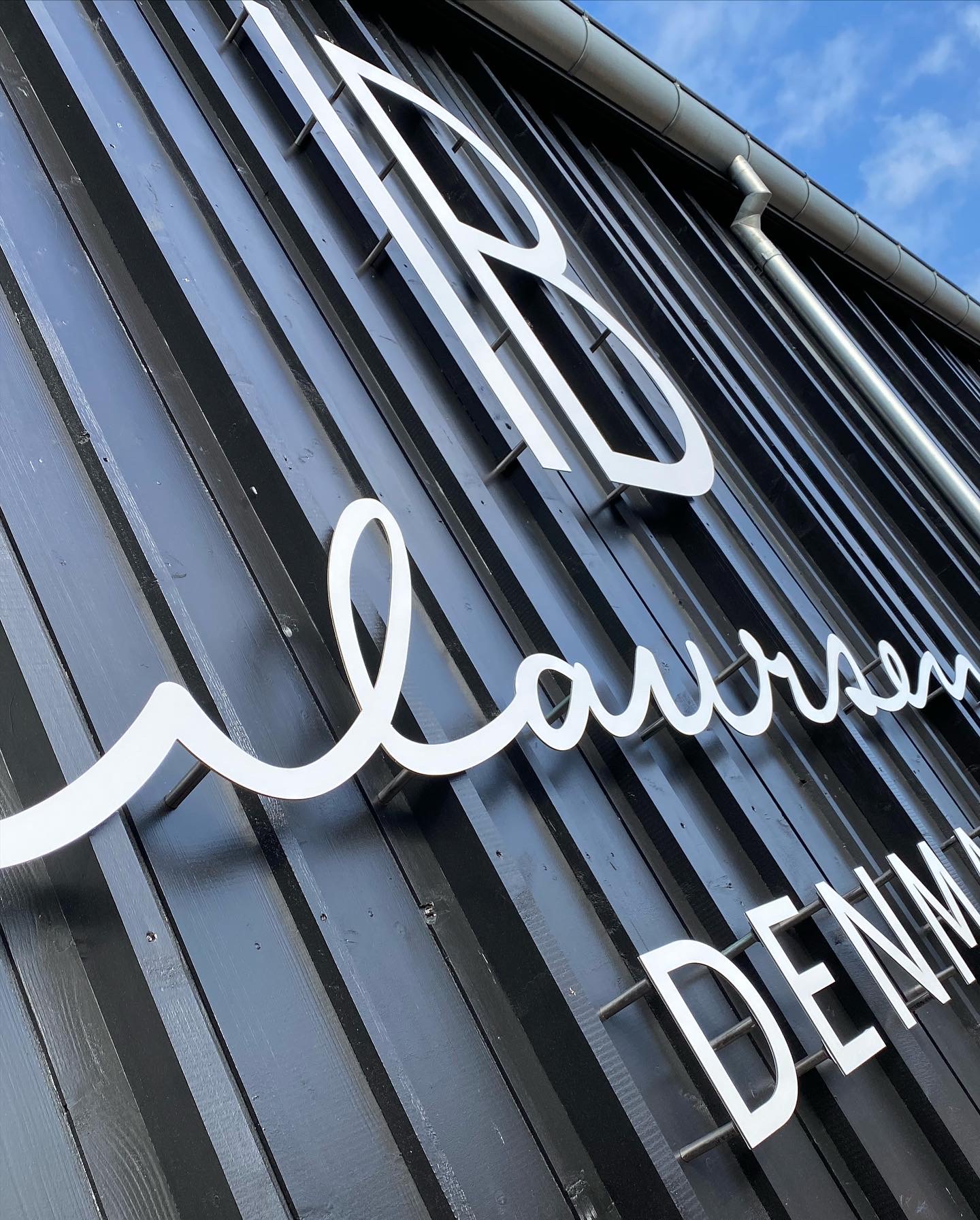 Facadelogo med stilrene facadebogstaver for Ib Laursen, monteret på bygning og skabt til markant og eksklusiv facadeskiltning.