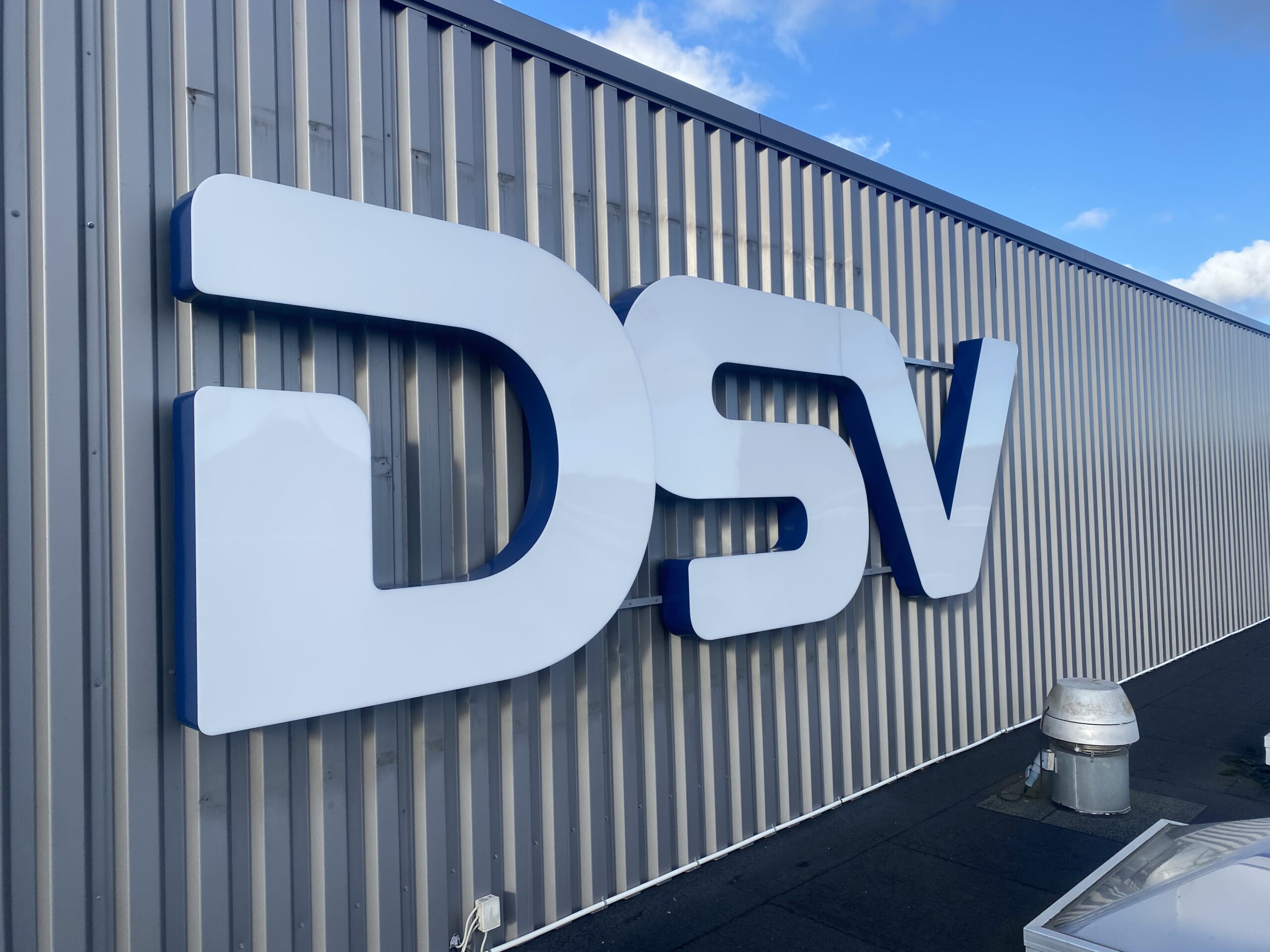 3D-bogstaver med hvid front og blå sider monteret på facaden hos DSV, fremstillet til markant og professionel facadeskiltning.